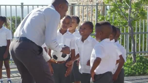 Leraar houden van de bal en praten met kinderen — Stockvideo