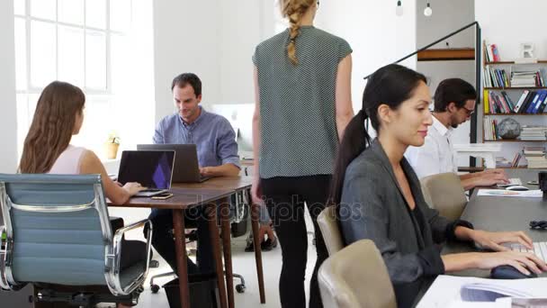 Une femme passe devant ses collègues au bureau — Video