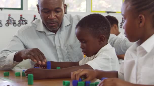 Teacher helping boy counting with blocks — Stock Video