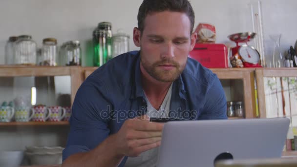 Hombre usando el ordenador portátil en la cocina — Vídeos de Stock