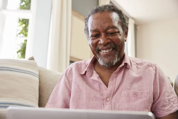 Uomo anziano sul divano utilizzando il computer portatile — Foto Stock