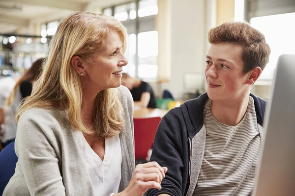 Lehrer mit männlichen Studenten, die in der Hochschulbibliothek am Computer arbeiten — Stockfoto