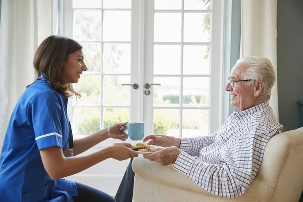 Infirmière servant une tasse de thé à un homme âgé — Photo