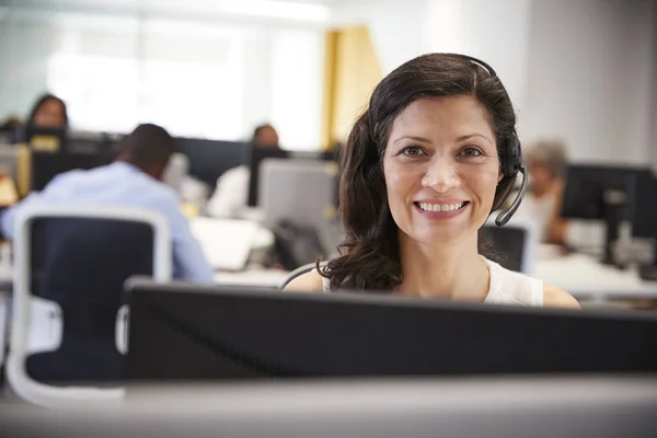 Mujer que trabaja en la computadora con auriculares en la oficina — Foto de Stock