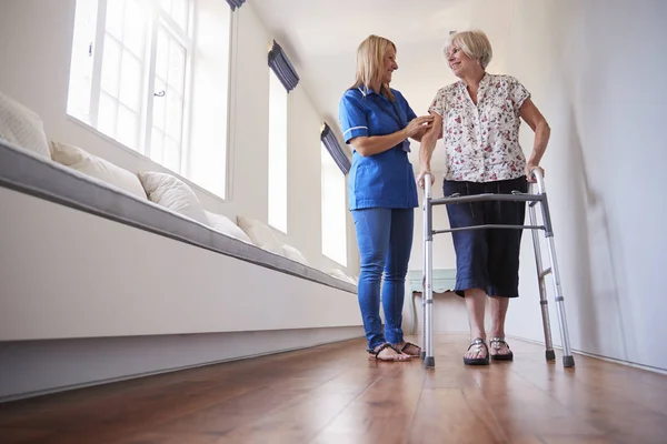 Pielęgniarka Pomagając Starszy Kobieta Użyć Balkonik Pełnej Długości — Zdjęcie stockowe
