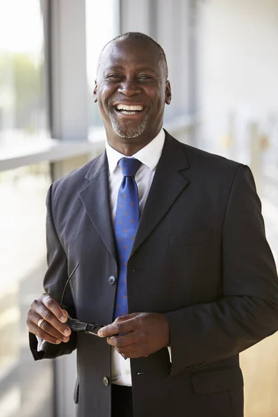 Hombre de negocios sonriente sosteniendo gafas — Foto de Stock