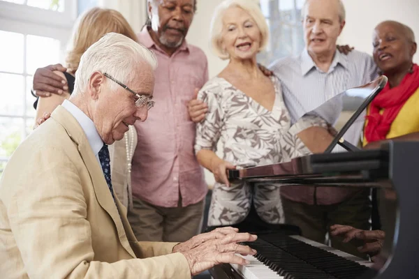 Seniors debout près du piano et chantant — Photo