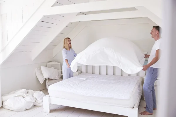 Par som bär pyjamas att göra säng — Stockfoto