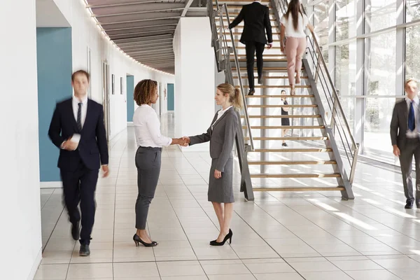 Affärskvinnor skakar hand i upptagna lobby — Stockfoto