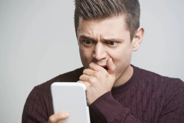 Chockad ung man använder smartphone — Stockfoto