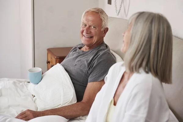 Pensionerade paret sitter i sängen — Stockfoto