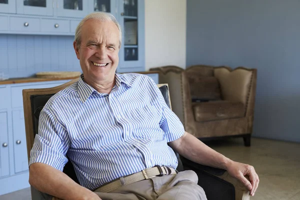 Homme âgé souriant assis sur une chaise — Photo