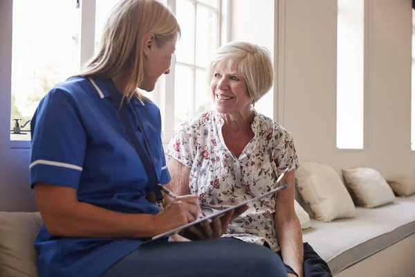 Senior Kvinna Sitter Med Sjuksköterska Att Göra Anteckningar Äldreboende — Stockfoto