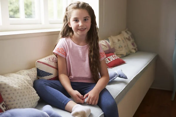 Sonriente joven sentada en la ventana — Foto de Stock