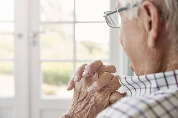 Senior man zit op zoek uit raam — Stockfoto