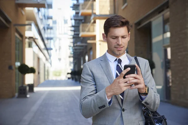 Biznesmen patrząc na telefon komórkowy — Zdjęcie stockowe