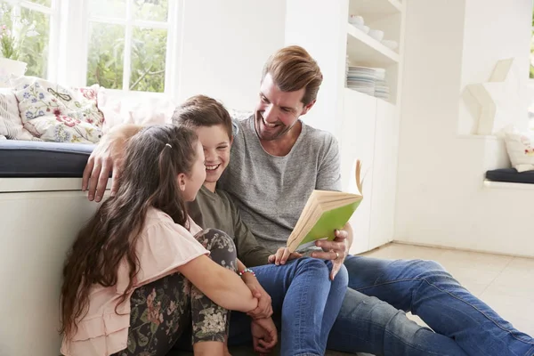 Отец читает книгу с сыном и дочерью — стоковое фото