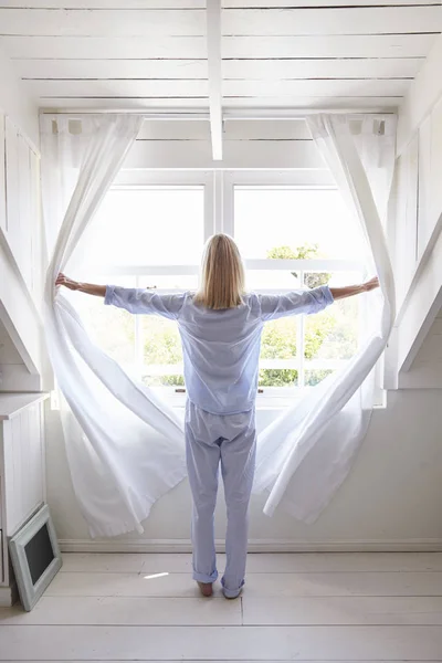 Frau öffnet Vorhänge — Stockfoto