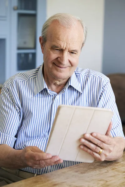 Старший человек дома с помощью планшета — стоковое фото