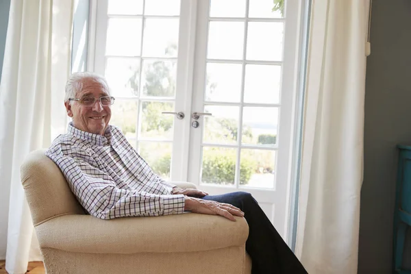 Senior man zit in een leunstoel — Stockfoto