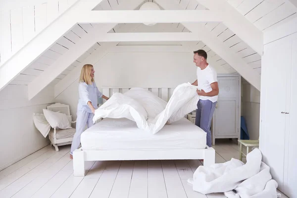 Pareja usando pijamas haciendo cama —  Fotos de Stock