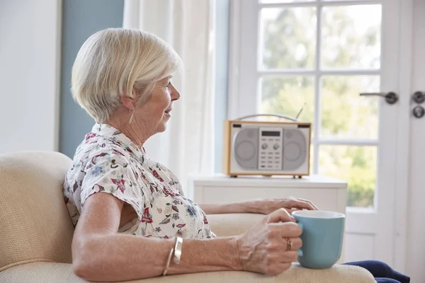 Ανώτερος Γυναίκα Πίνοντας Τσάι Και Ακούτε Ραδιόφωνο Στο Σπίτι — Φωτογραφία Αρχείου