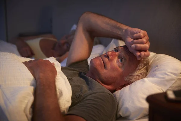 Беспокойный пожилой человек в постели ночью — стоковое фото
