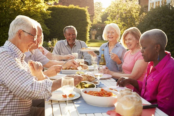 Senior vrienden genieten van diner in de buitenlucht — Stockfoto