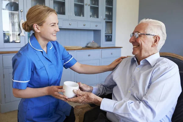 Verpleegkundige Senior Man kopje thee te geven — Stockfoto