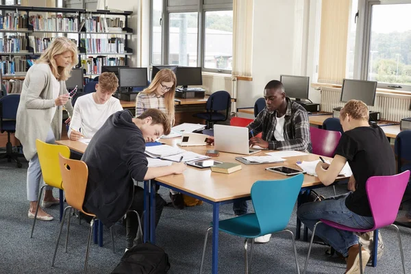 Leraar helpen studenten aan tafel — Stockfoto