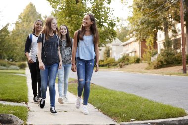 Four young teen girls walking to school together, front view clipart