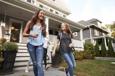 Young teen girlfriends leaving a house for school clipart