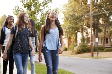 Four young teen girls walking to school, front view close up clipart