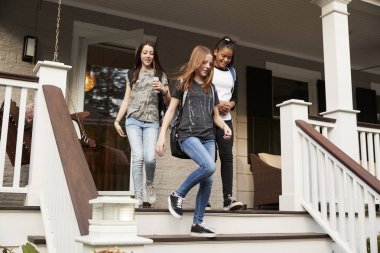 Three teen girls leaving house with school bags clipart