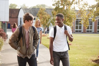 Male Teenage Students Walking Around College Campus Together clipart
