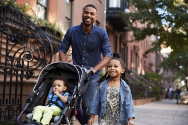 Father and two daughters taking a walk down the street, close up clipart