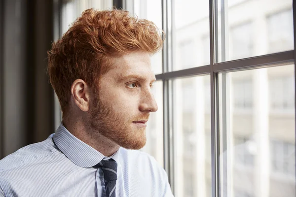 Genç Kırmızı Saçlı Sakallı Işadamı Pencereden Dışarı Bakıyor — Stok fotoğraf