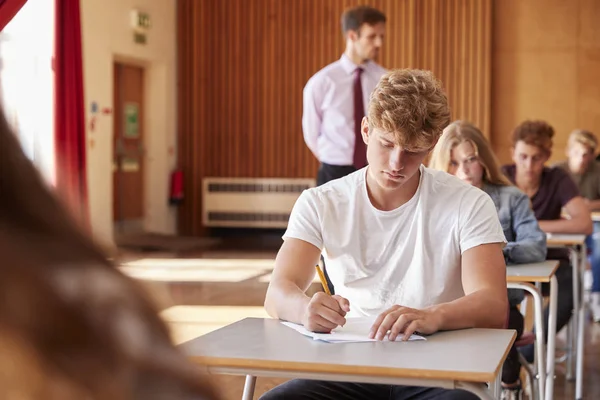 Estudiantes Adolescentes Sentados Examen Con Profesor Vigilando —  Fotos de Stock