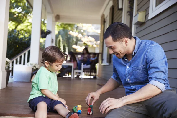 父と息子が一緒におもちゃで遊んでの家のポーチに座ってください — ストック写真