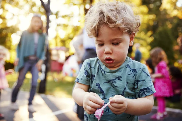 Toddler Chłopiec Rozpakowanie Lizaka Zewnątrz — Zdjęcie stockowe