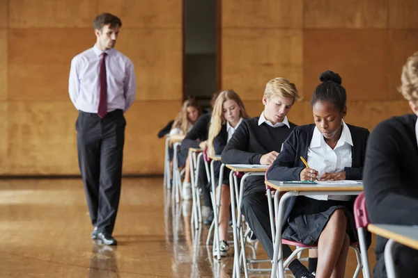 Teenage Studenti Sedí Vyšetření Učitelem Invigilating — Stock fotografie