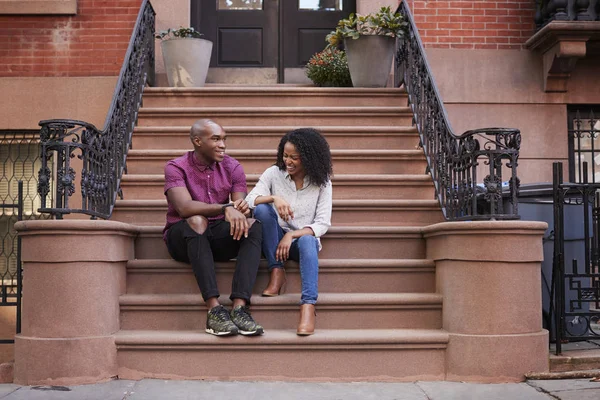 Couple Sit And Talk On Stoop Of Brownstone In New York City