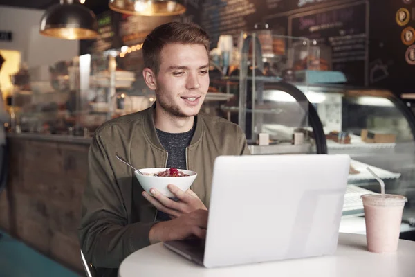 Hombre Joven Usando Ordenador Portátil Café Mientras Come Desayuno —  Fotos de Stock