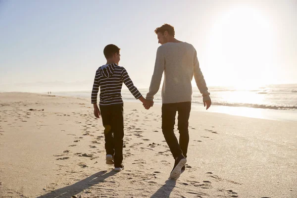 冬の浜辺で手をつないで歩く親子の後姿 — ストック写真