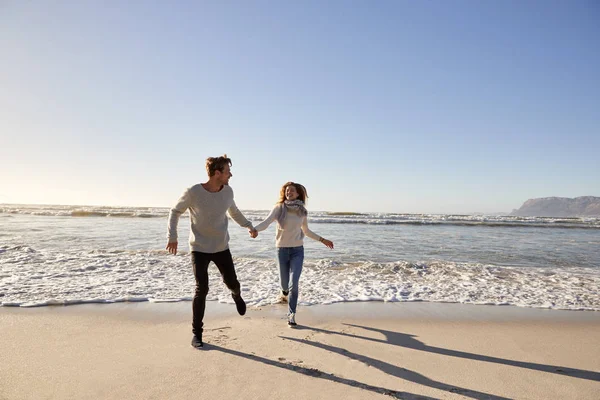 夫妇有乐趣一起跑在冬天海滩一起 — 图库照片