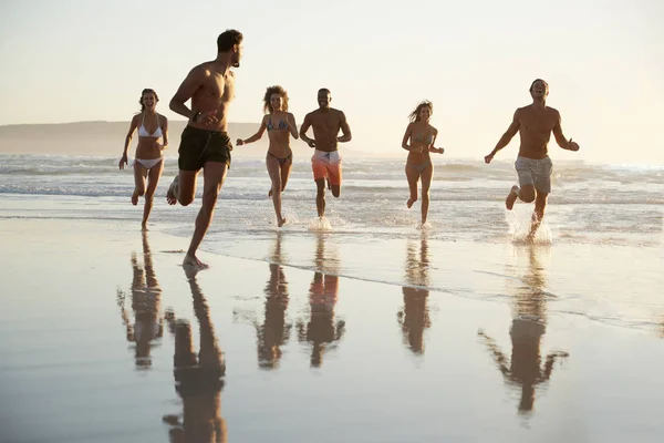 Grupa Przyjaciół Biegają Przez Fale Razem Wakacjach Plaży — Zdjęcie stockowe