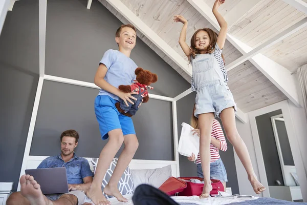 Excited Children Jump Bed Parents Pack Vacation — Stock Photo, Image