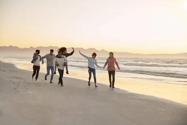 一群快乐的朋友一起沿着冬季海滩一起奔跑 — 图库照片