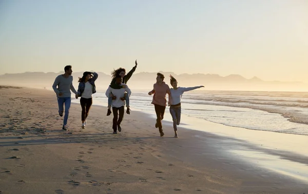 一群快乐的朋友一起沿着冬季海滩一起奔跑 — 图库照片