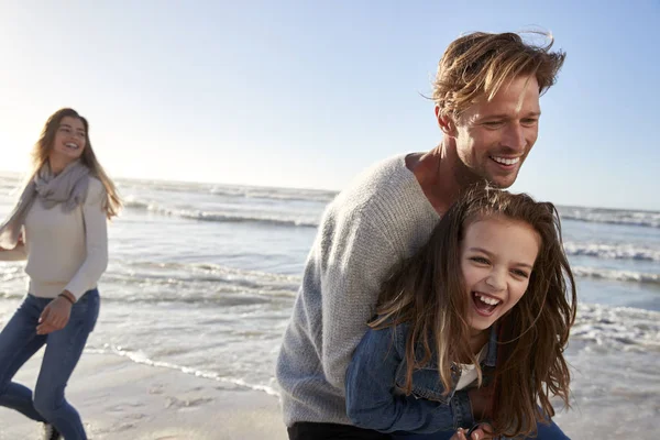 与女儿一起在冬天海滩乐趣的父母一起 — 图库照片